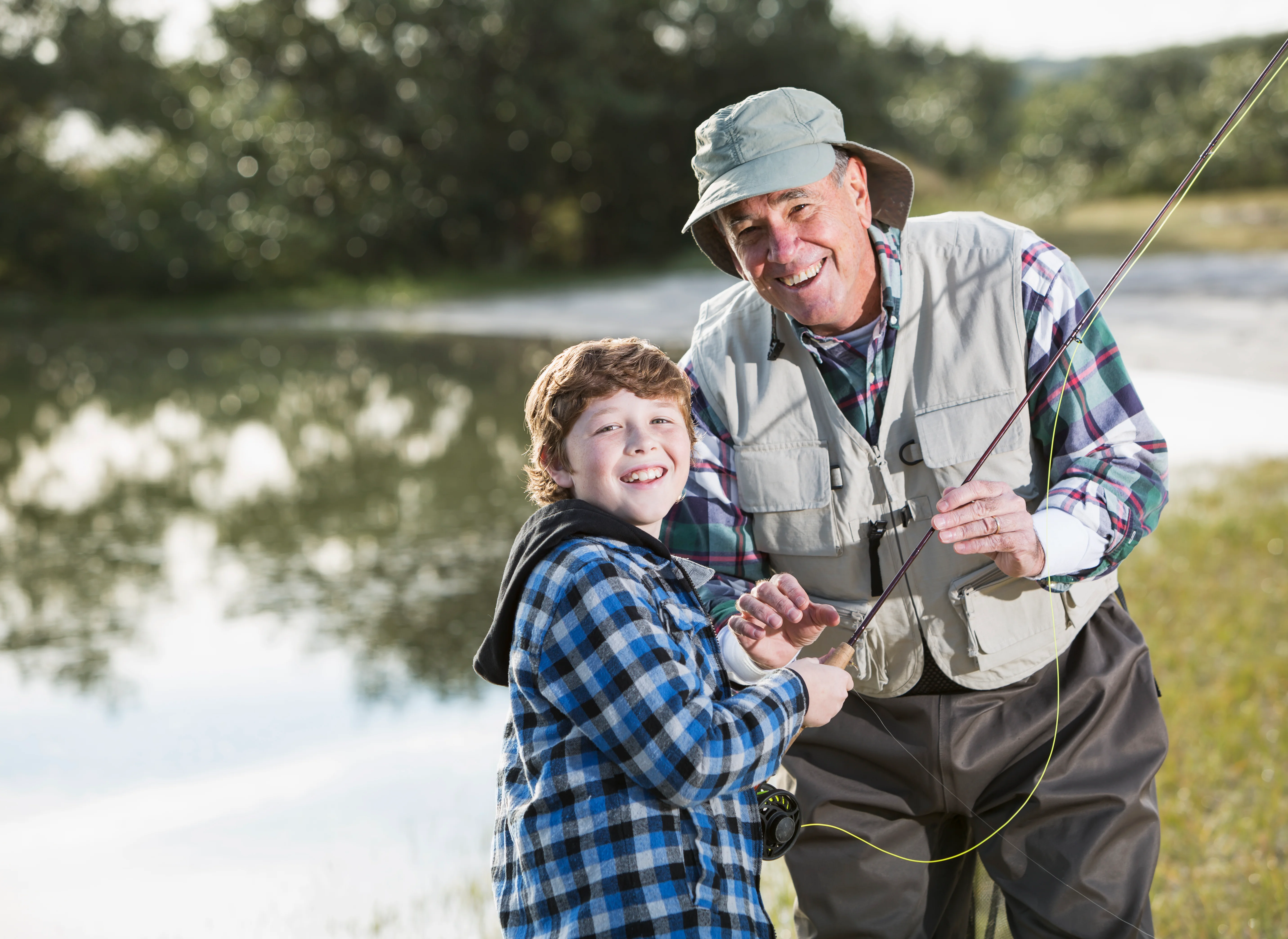 Grandfather and grandson fishing by the river