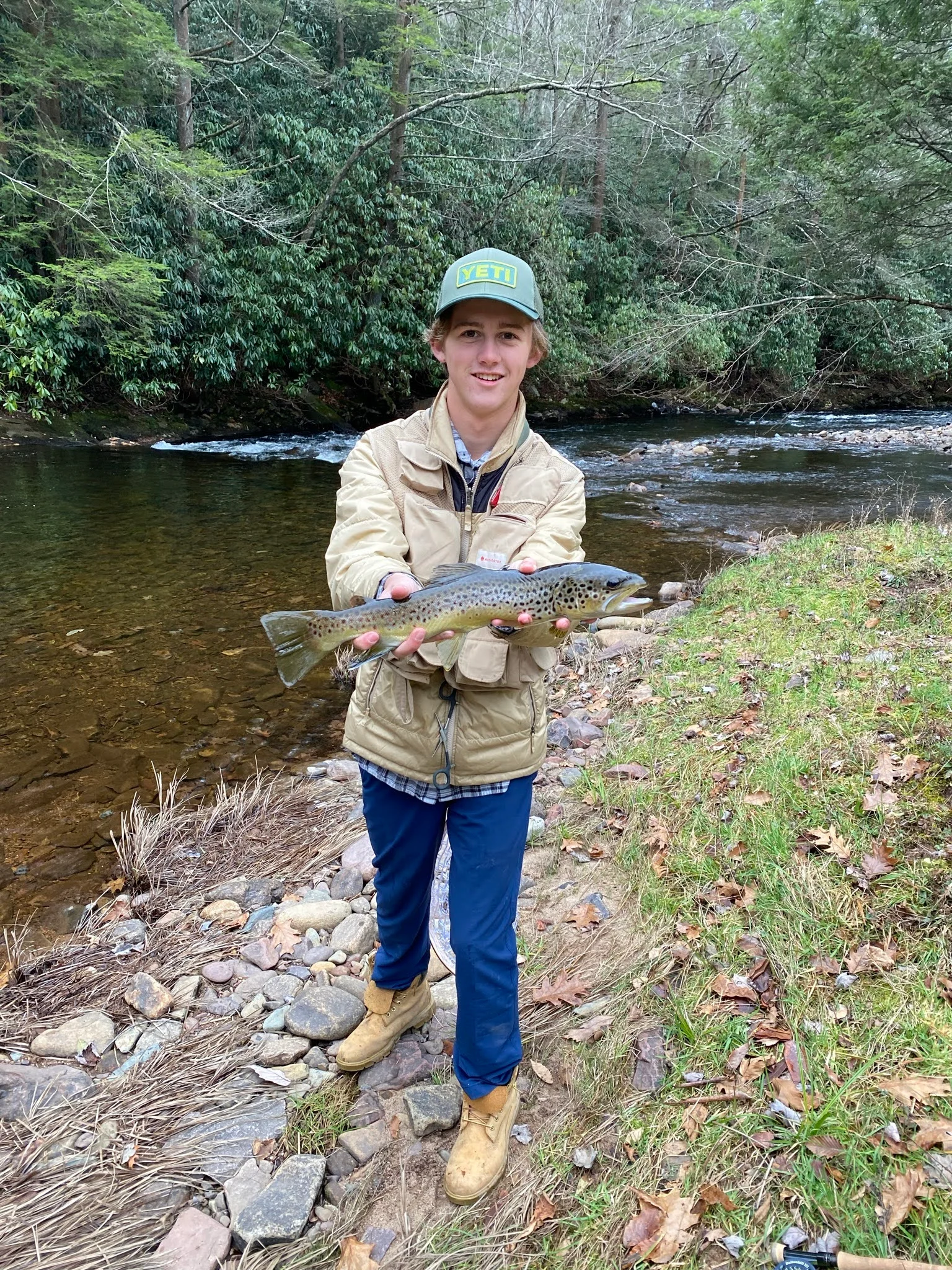 Young man proudly holding a freshly caught trout